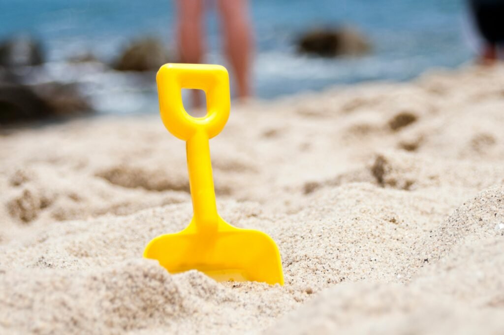 Bright yellow shovel in sandy beach setting, perfect summer fun imagery.